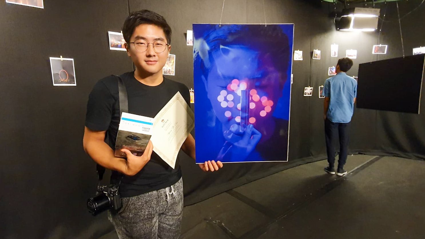 MDIS media student poses with the photograph that he took.