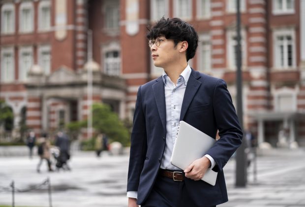 male asian business student in formal wear carrying a laptop