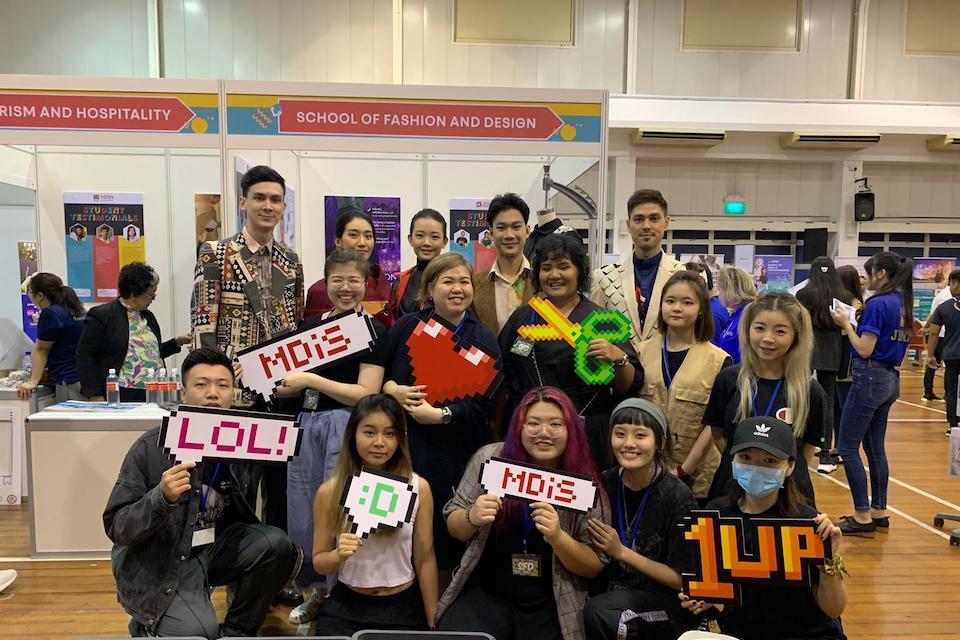 MDIS fashion students posing with photo booth items at the open house.